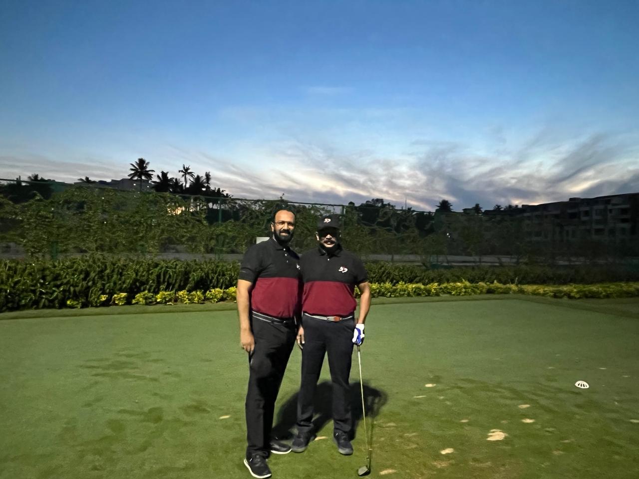 Govind Raj and a playing partner on a golf green at dusk