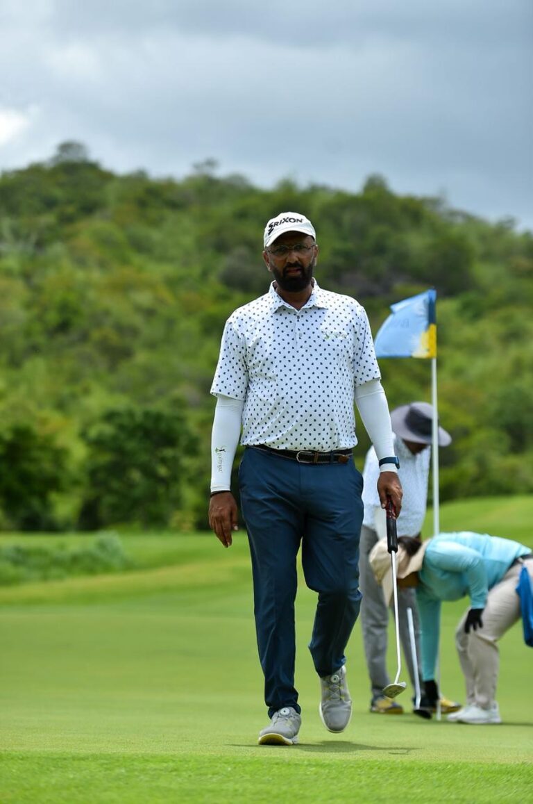 Govind Raj walking a green golf fairway with hills behind