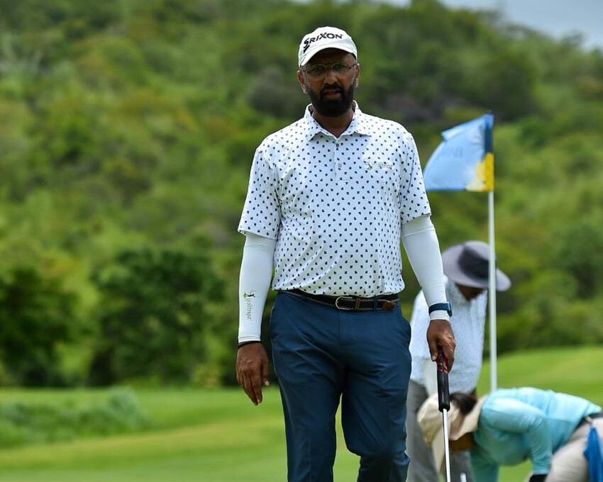 Govind Raj walking a green golf fairway with hills behind