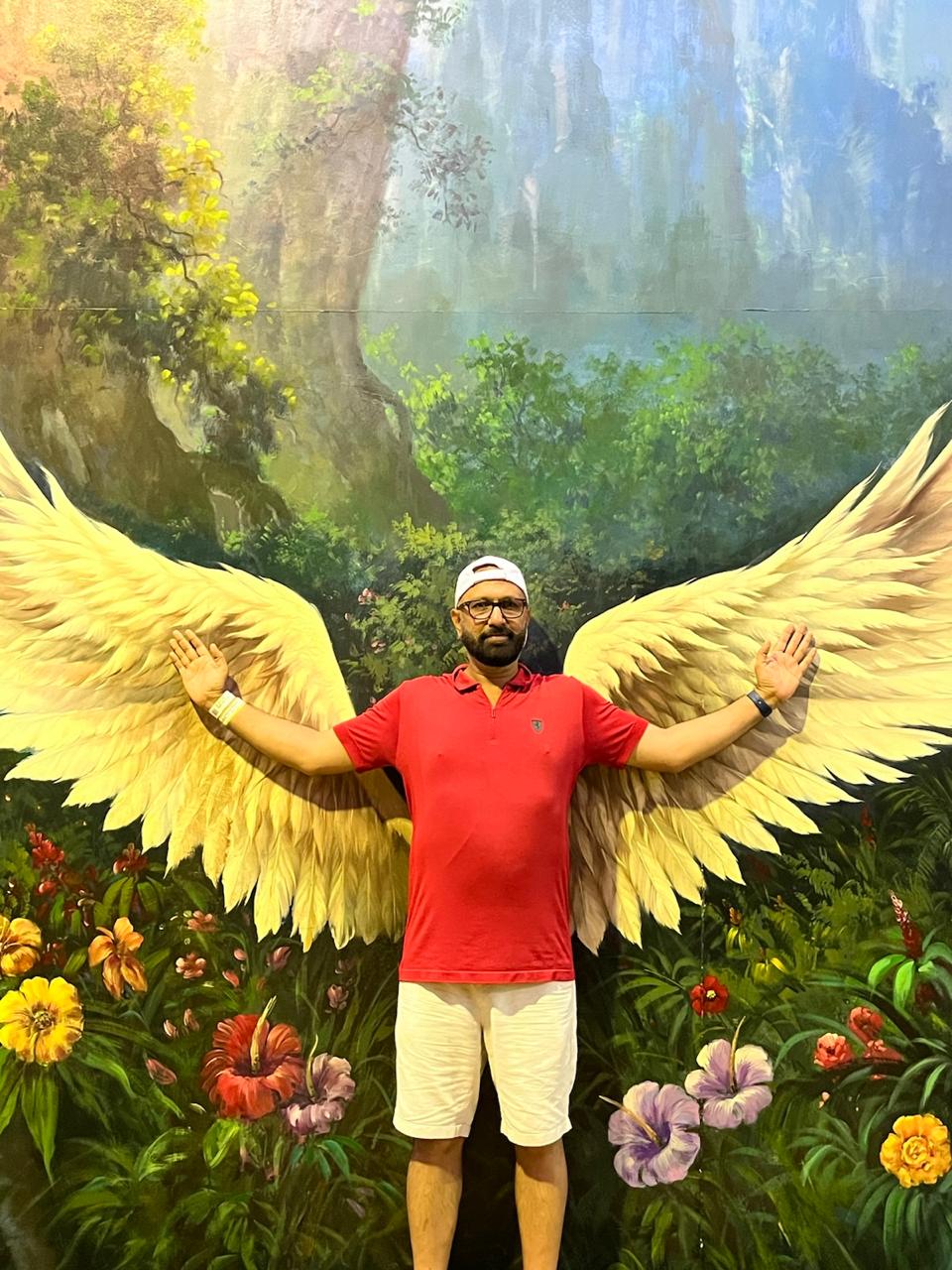 Govind Raj standing in front of a painted wings mural